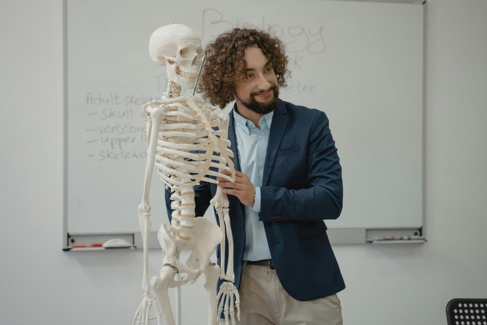 A biology teacher demonstrates the human skeleton model in an engaging classroom setting.